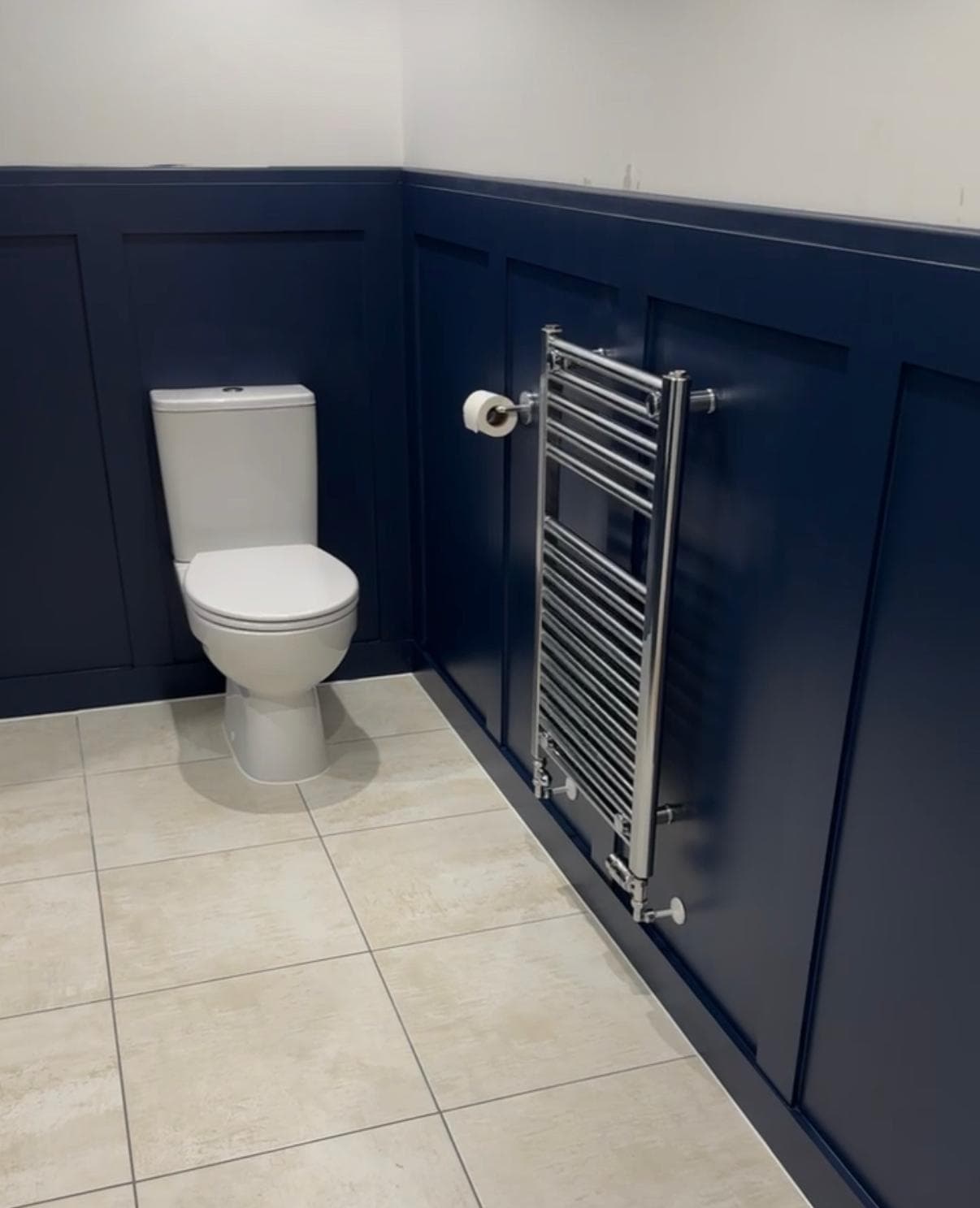Navy panelled bathroom with chrome towel rail