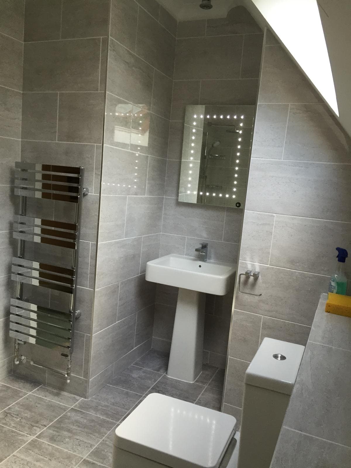 Loft en-suite with grey stone-effect tile and illuminated mirror