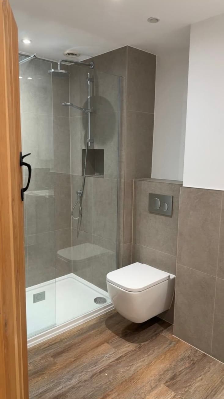 Grey tiled walk-in shower with wall-hung toilet