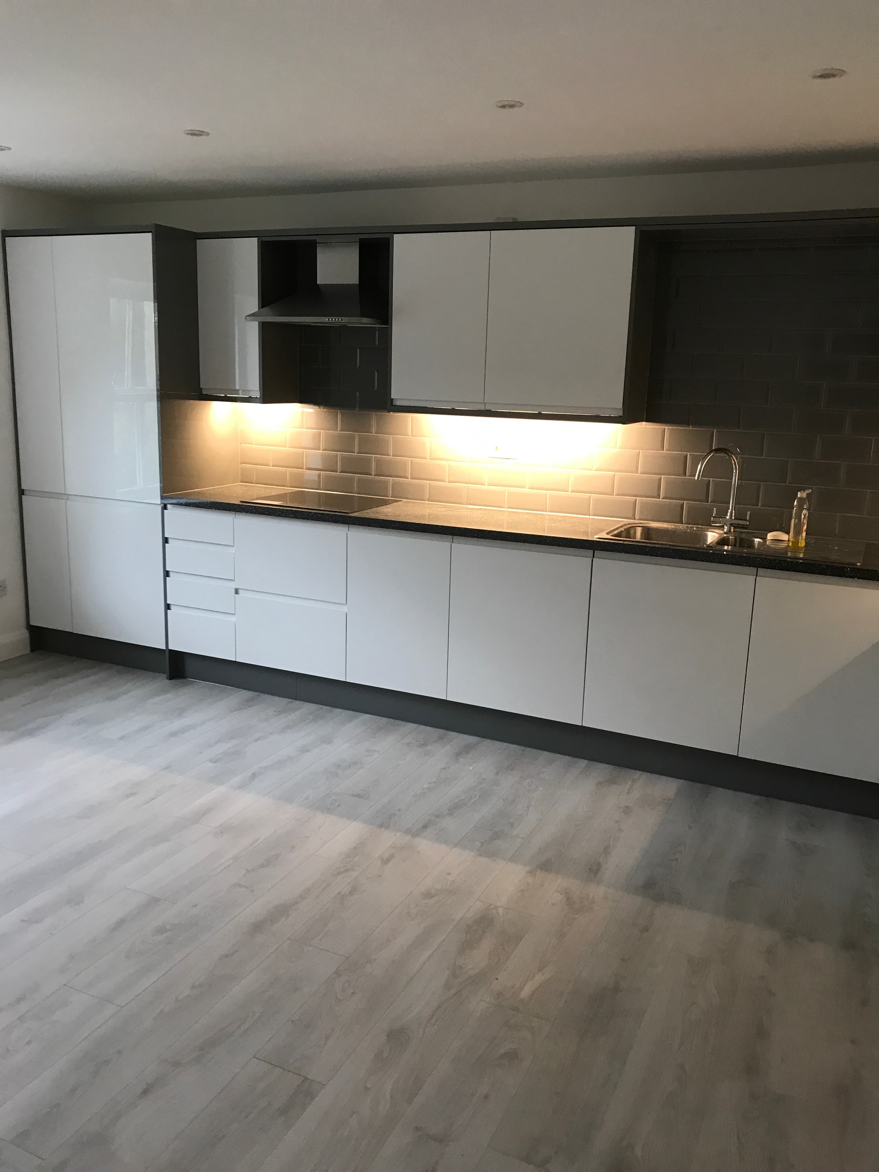Gloss white kitchen with dark worktop and grey metro tile