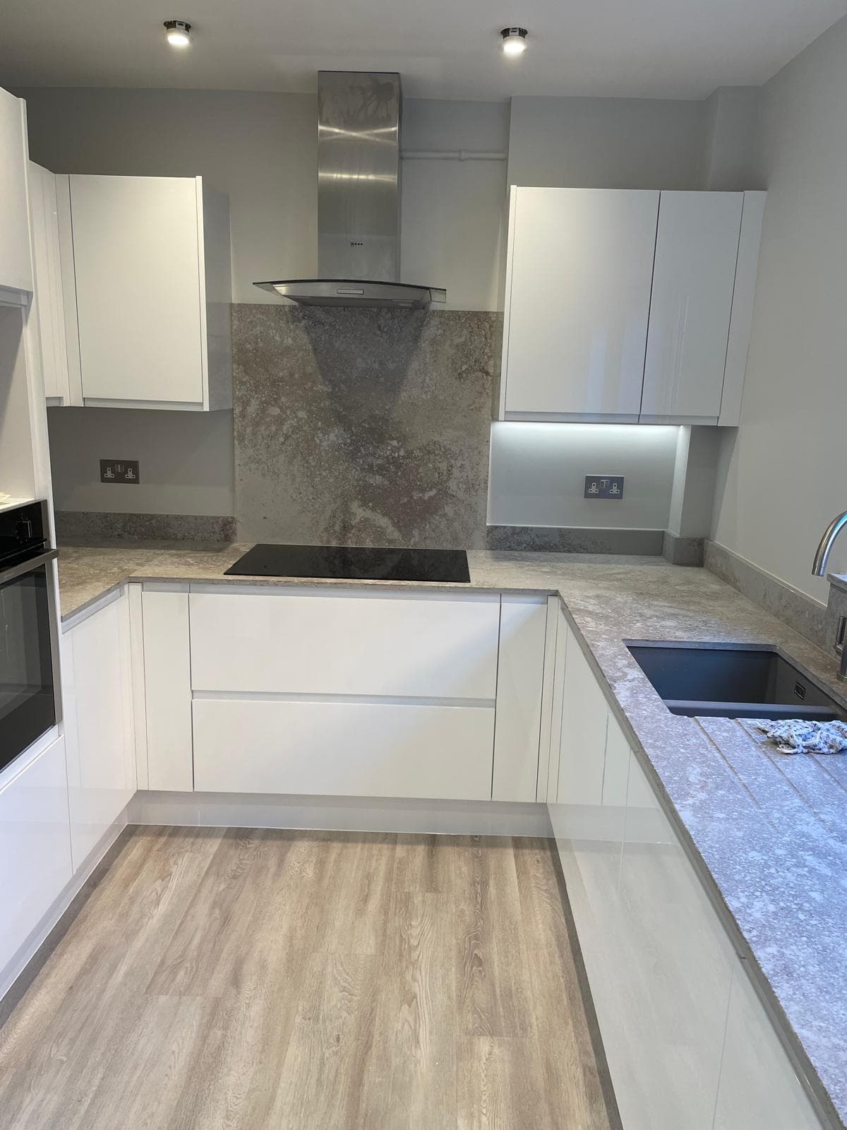 Gloss white kitchen with slate-effect splashback